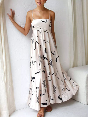 Ivory spaghetti strap maxi dress with abstract black print, square neckline, and flowing skirt.