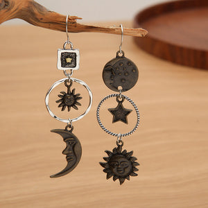 Cosmic asymmetry drop earrings in copper feature sun, moon, and star charms with unique celestial designs.