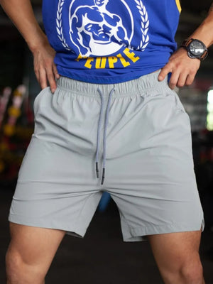 Gray athletic shorts with drawstring and pockets, shown on a person wearing a blue graphic tank top.