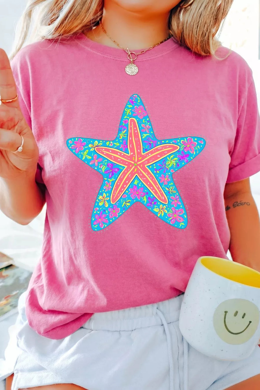Pink cotton t-shirt with a blue starfish graphic filled with colorful flowers.