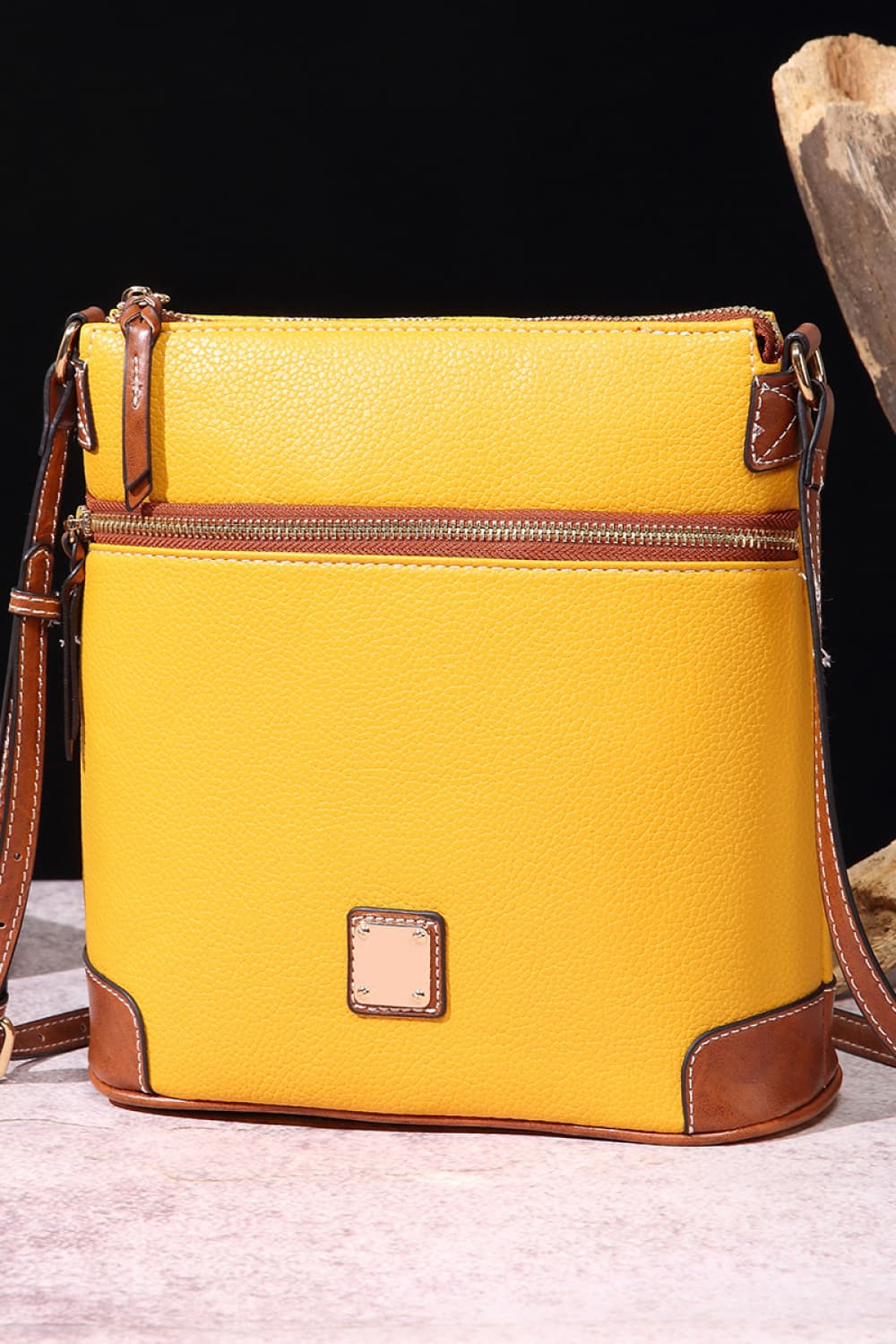 Yellow leather crossbody bag with brown trim and zipper details.