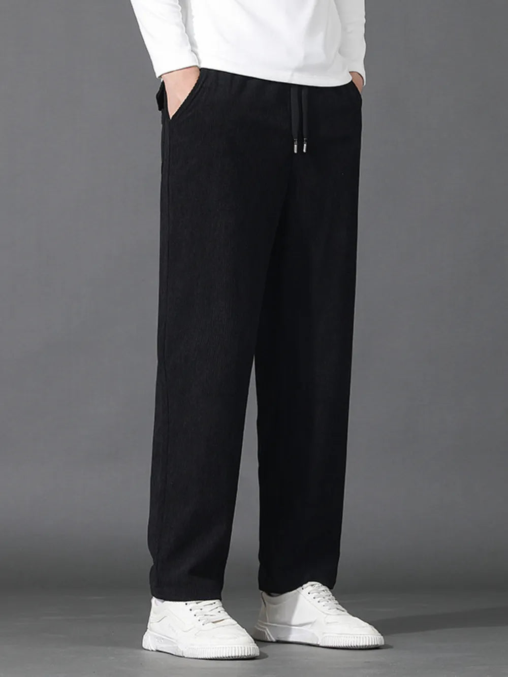 Black sweatpants with drawstring waist and pockets, styled with white sneakers.