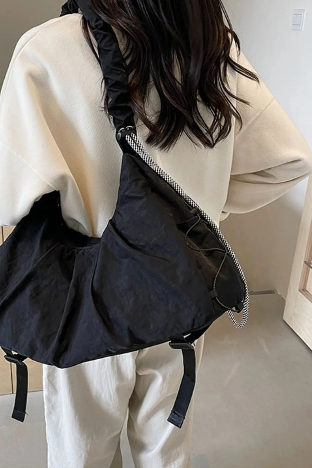 Black gathered crescent shoulder bag with ruched strap and drawstring detail