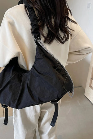 Black gathered crescent shoulder bag with ruched strap and drawstring detail