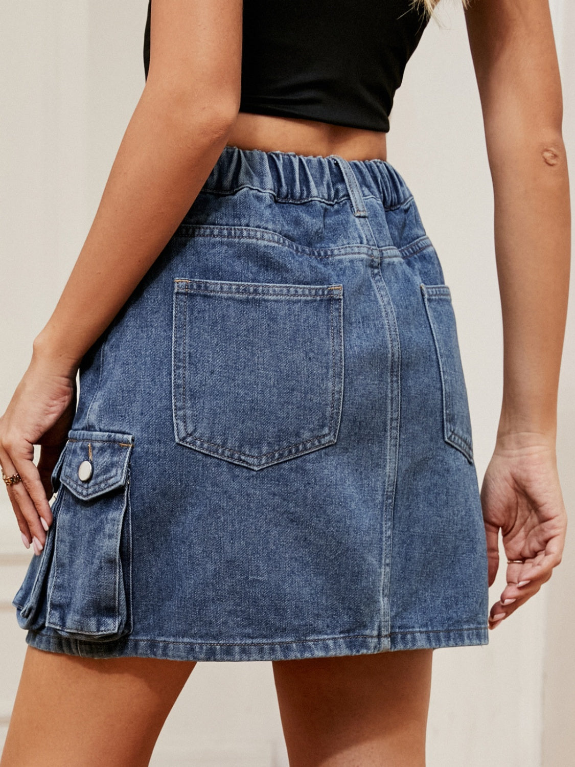 Denim cargo skirt in dark blue with elastic waist and utility pockets.