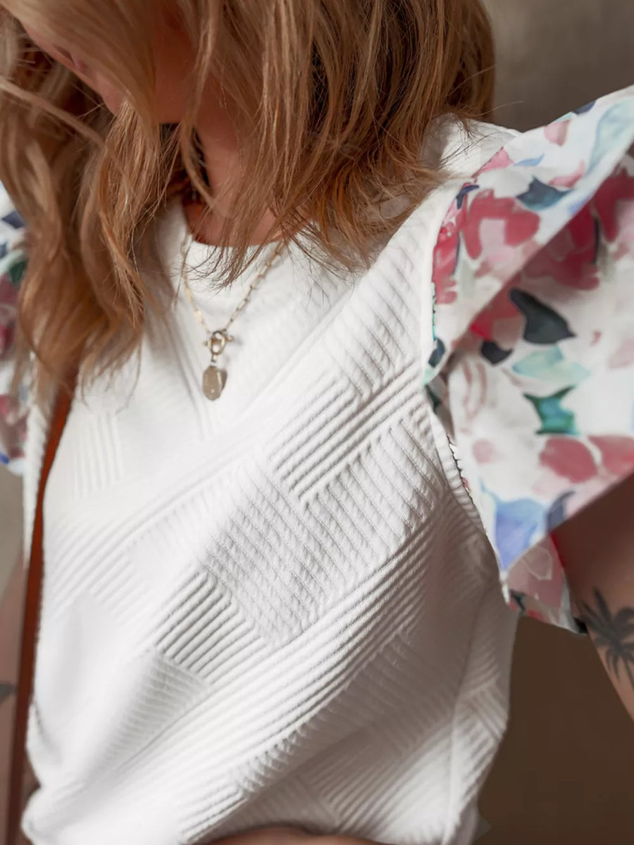 White geometric knit top with floral ruffled sleeves
