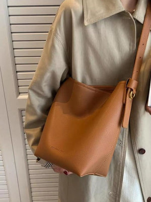 Brown minimalist PU leather shoulder bag with adjustable strap and gold buckle detail.