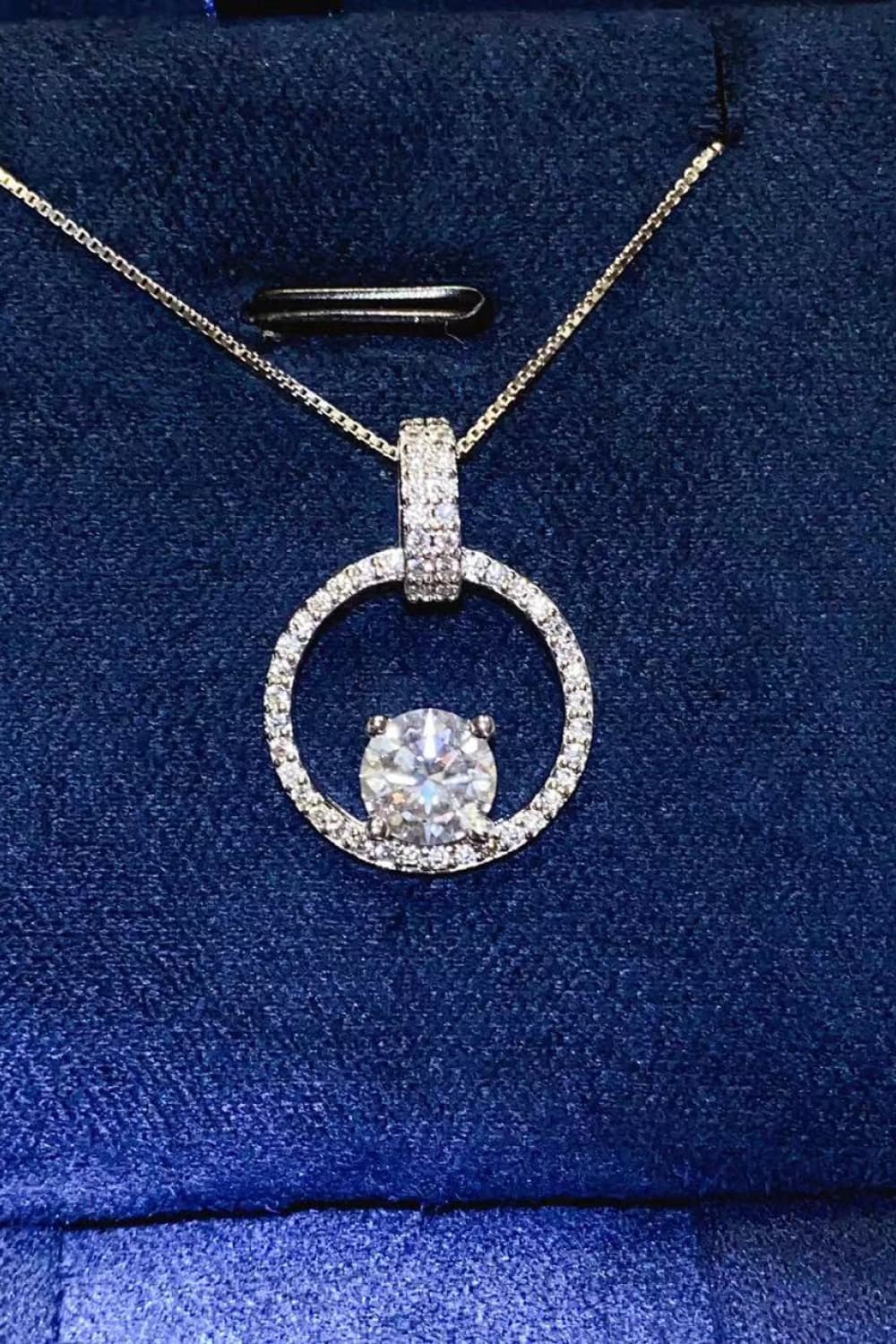 Silver moissanite halo circle pendant necklace with pave set stones on a sterling silver chain.