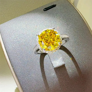 Sterling silver ring with large yellow moissanite center stone and halo of small stones.