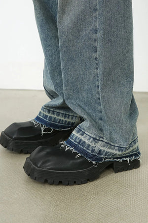 Distressed wide-leg denim jeans in medium wash with raw hem detail.