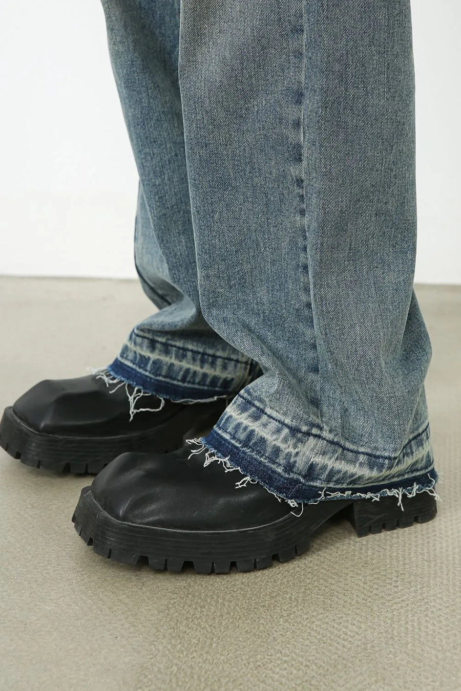 Distressed wide-leg denim jeans in medium wash with raw hem detail.