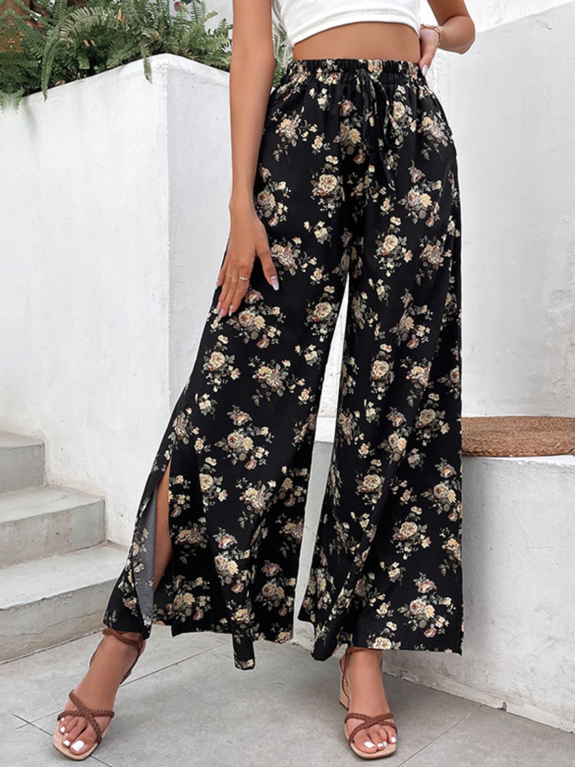 Black floral palazzo trousers with split hems and a drawstring waist.