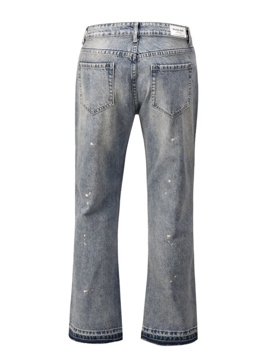 Distressed wash bootcut jeans with raw hem detail in medium blue denim.