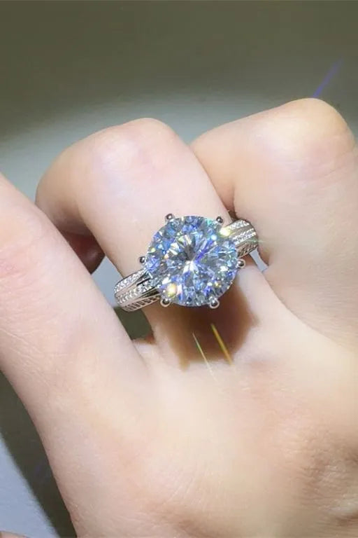 Silver moissanite ring with a large round-cut center stone and detailed band.
