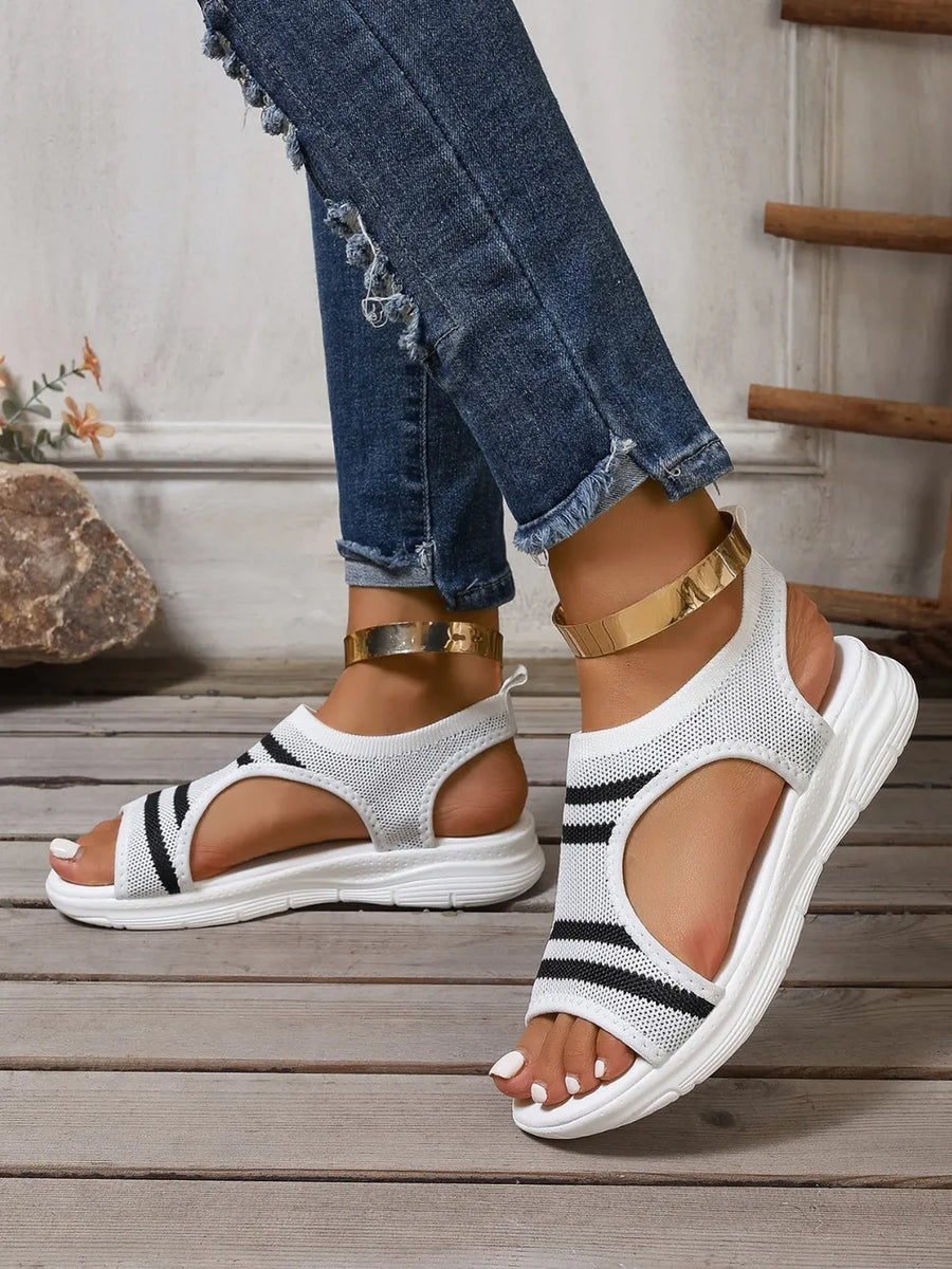 White knit sport sandals with black stripes and gold ankle straps.