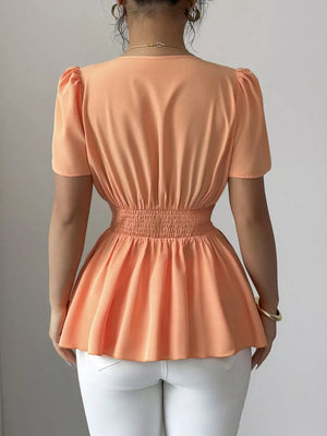 Orange polyester peplum blouse with smocked waist and puff sleeves.