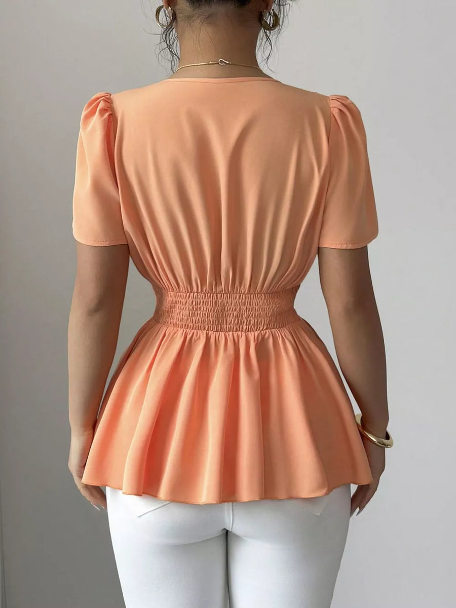 Orange polyester peplum blouse with smocked waist and puff sleeves.