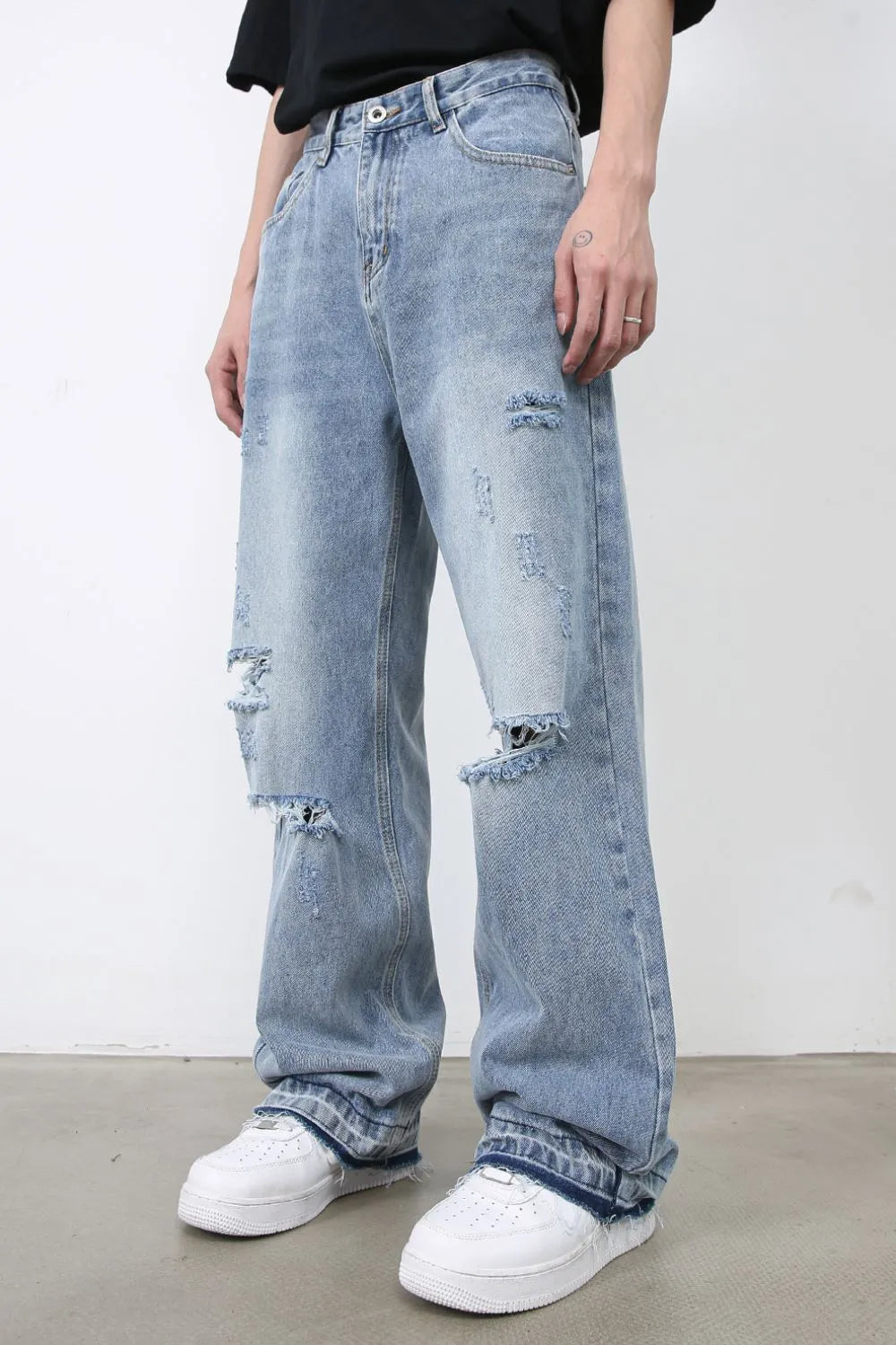 Light blue distressed wide-leg denim jeans with raw hem detail and ripped knees.