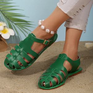Green woven leather T-strap sandals with buckle closure and pearl anklet.