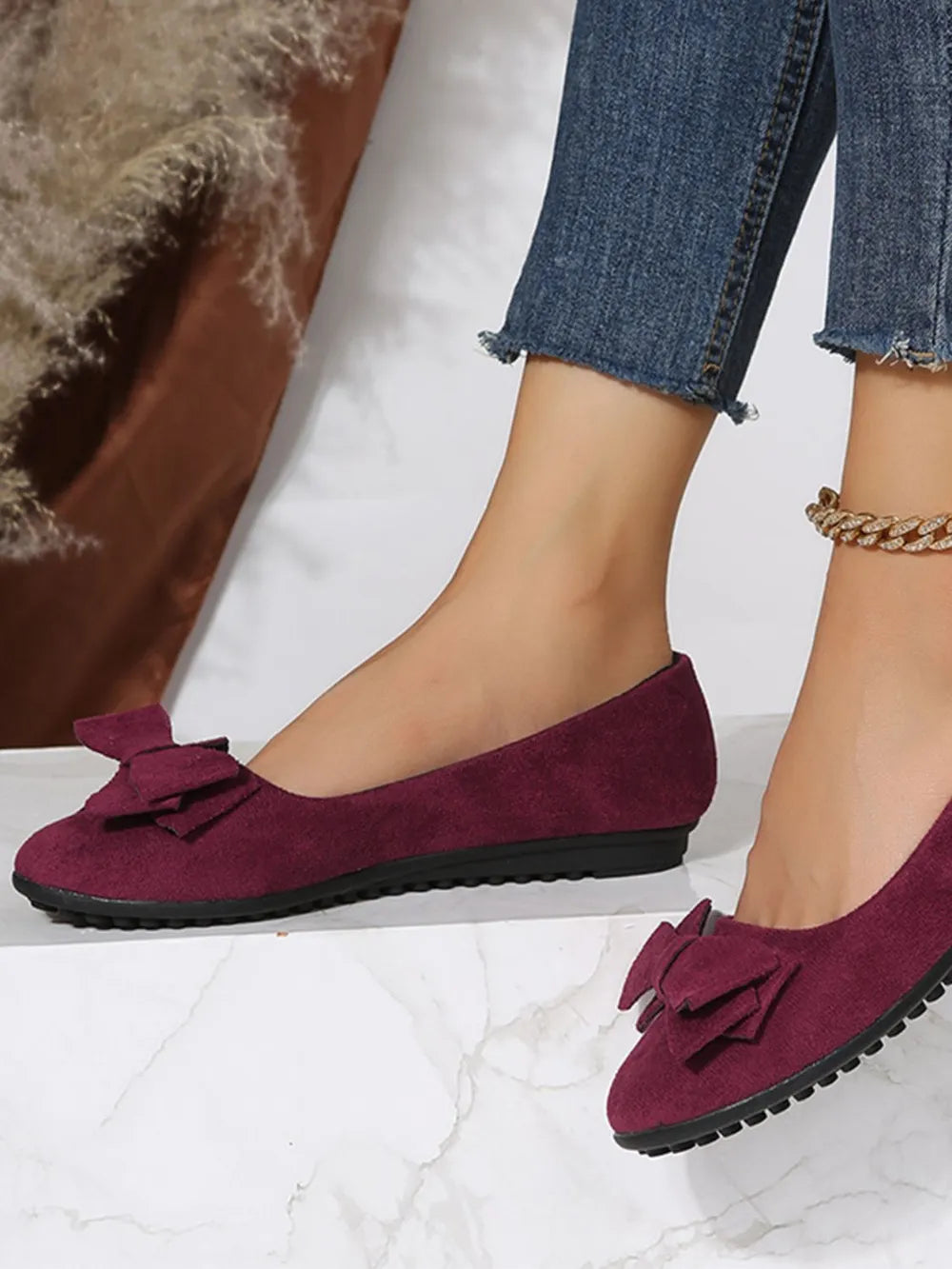 Burgundy suede pointed-toe flats with bow embellishment.