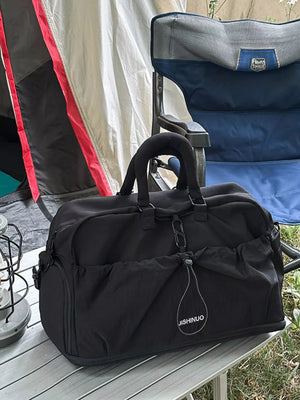 Black crinkled nylon drawstring travel bag with side pockets and top handles.