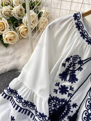 White blouse with intricate navy embroidery and balloon sleeves.