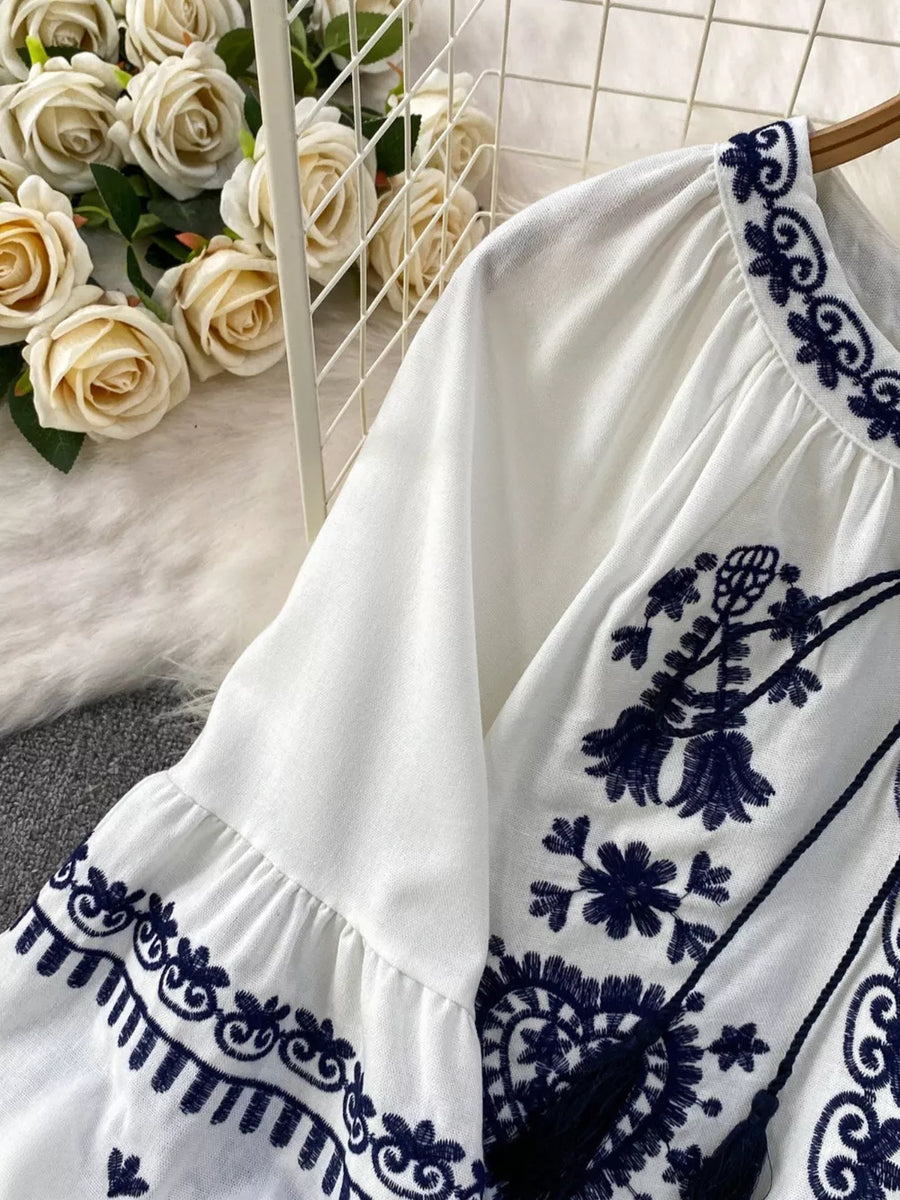 White blouse with intricate navy embroidery and balloon sleeves.