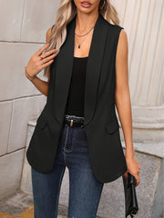 Black shawl collar sleeveless vest coat with two front pockets, worn open over a black top and jeans.