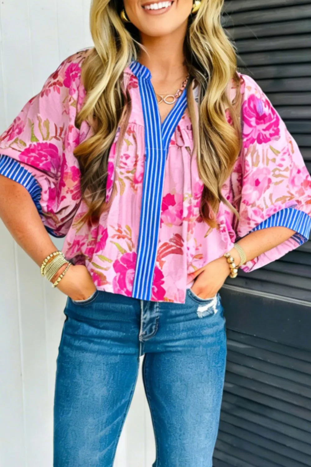 Pink floral v-neck blouse with blue striped accent and short sleeves