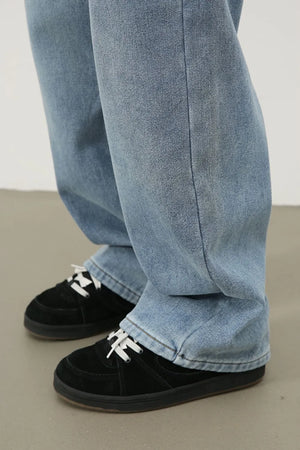 Oversized fade wash denim jeans in medium blue, shown with black sneakers.