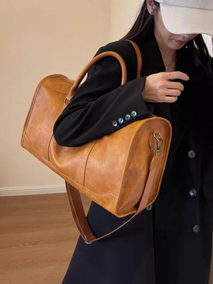 Cognac vintage leather duffle bag with top handles and adjustable strap.