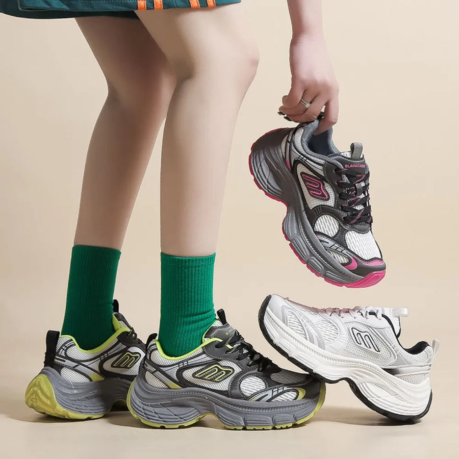 Chunky retro runner sneakers in white, grey, and neon yellow with pink accents.