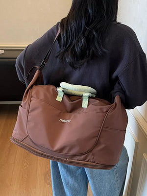 Brown Oxford cloth travel duffel bag with side pockets and light green handles.