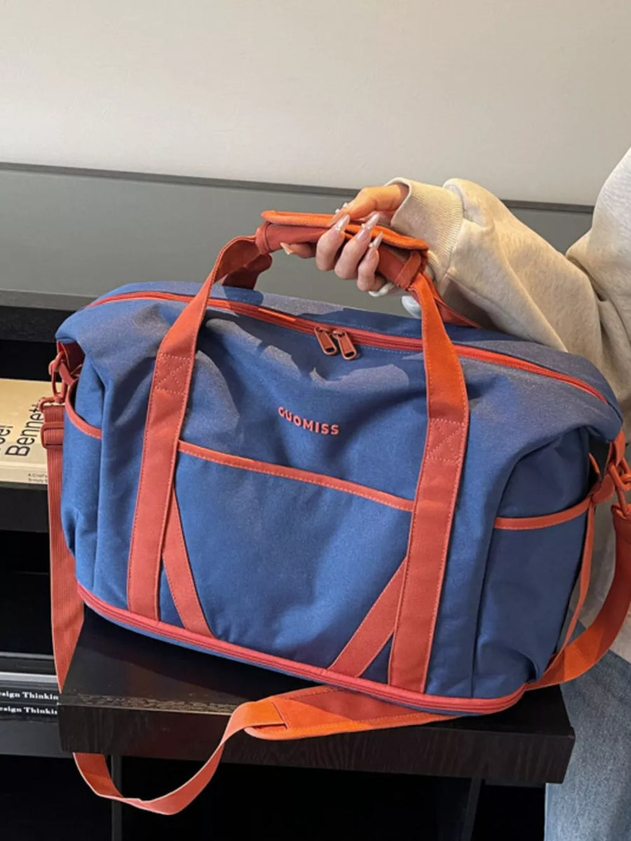 Blue duffel bag with orange trim and straps, featuring a zippered main compartment and side pockets.