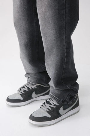 Faded wash baggy jeans in dark denim, styled with sneakers.