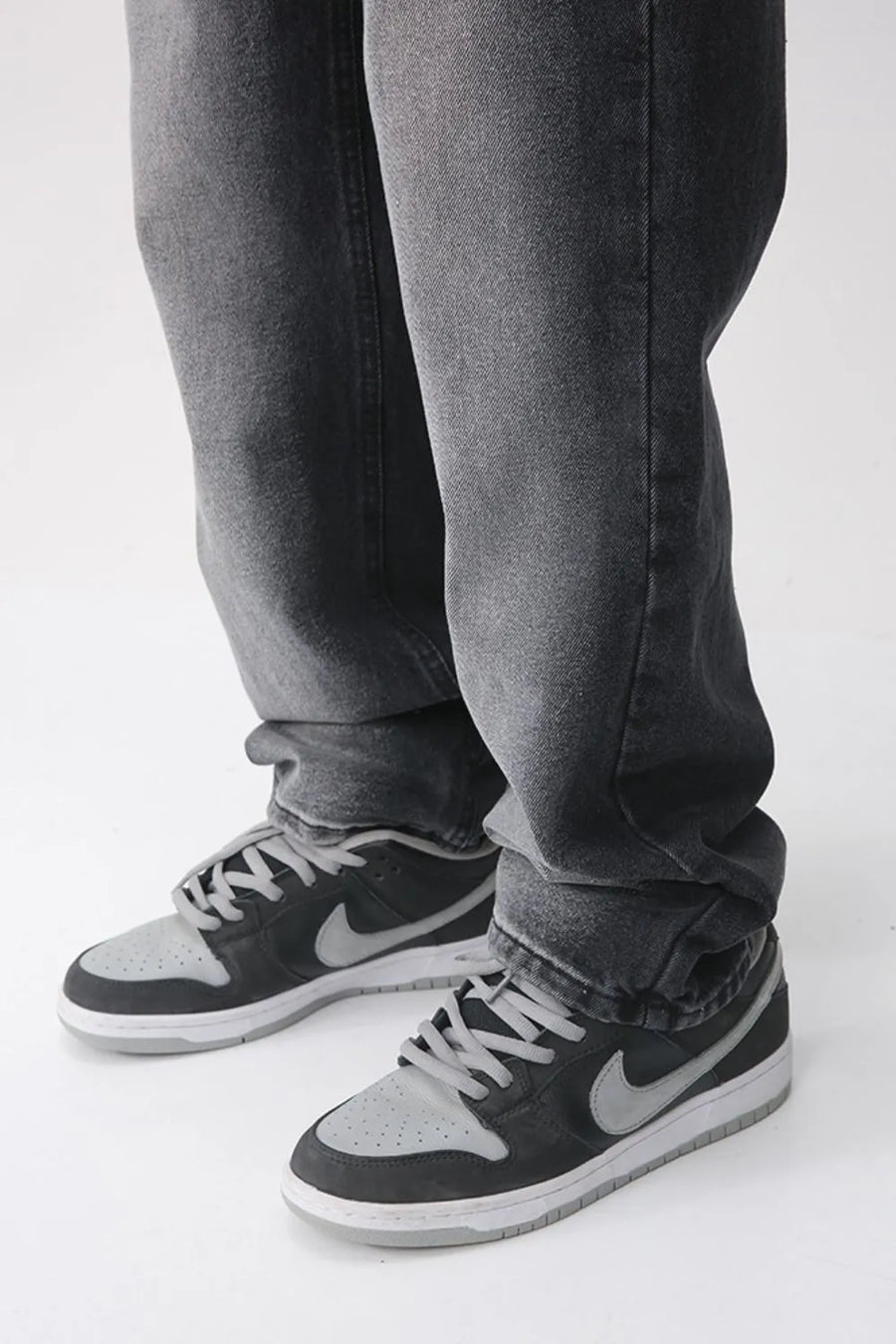 Faded wash baggy jeans in dark denim, styled with sneakers.