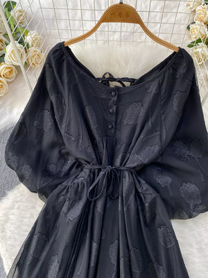 Black chiffon maxi dress with floral embroidery, button-down front, tie waist, and puff sleeves.