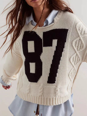black pullover sweater featuring cable-knit and graphic print