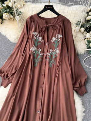 Brown cotton maxi dress with embroidered floral detail and tie neck.