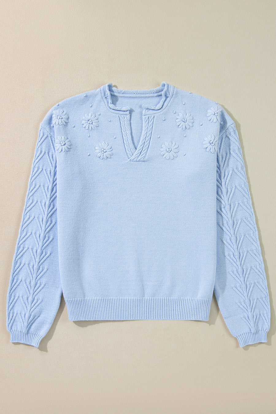 Light blue sweater with floral embellishments and cable knit sleeves