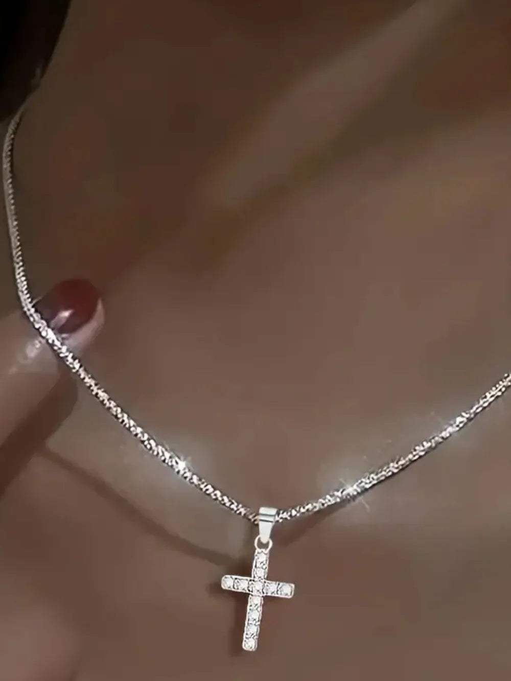 Sparkling silver cross pendant necklace with rhinestones on a delicate chain.