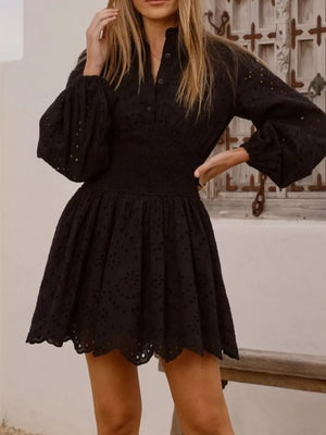 Black eyelet mini dress with balloon sleeves, smocked waist, and scalloped hem.