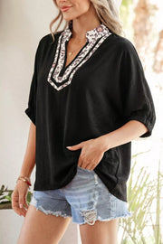 Black polyester tunic with leopard print notched neckline and short sleeves.