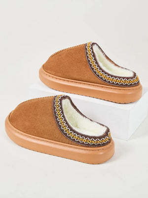 Caramel shearling house slippers with embroidered trim and white faux fur lining.