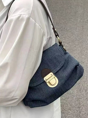 Mini denim shoulder bag with gold turn-lock closure and brown trim.