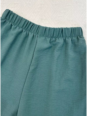 Turquoise cropped vest and wide-leg pants ensemble with elastic waistband and textured fabric.