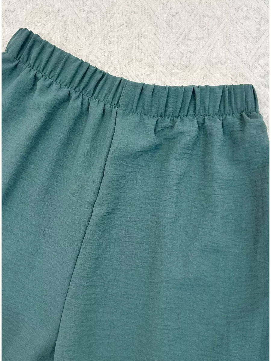 Turquoise cropped vest and wide-leg pants ensemble with elastic waistband and textured fabric.