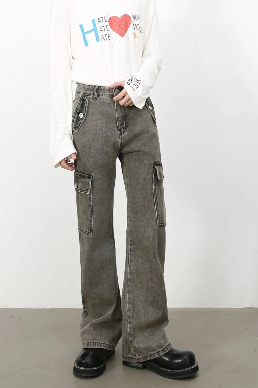 Faded denim flare cargo pants in dark gray with multiple pockets and button details.