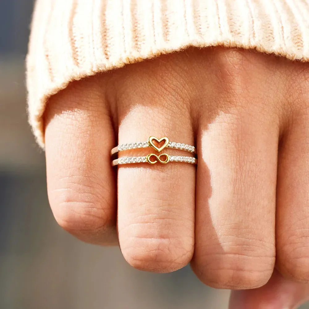 Double band ring with heart and infinity symbols, adorned with zircon stones, silver tone.