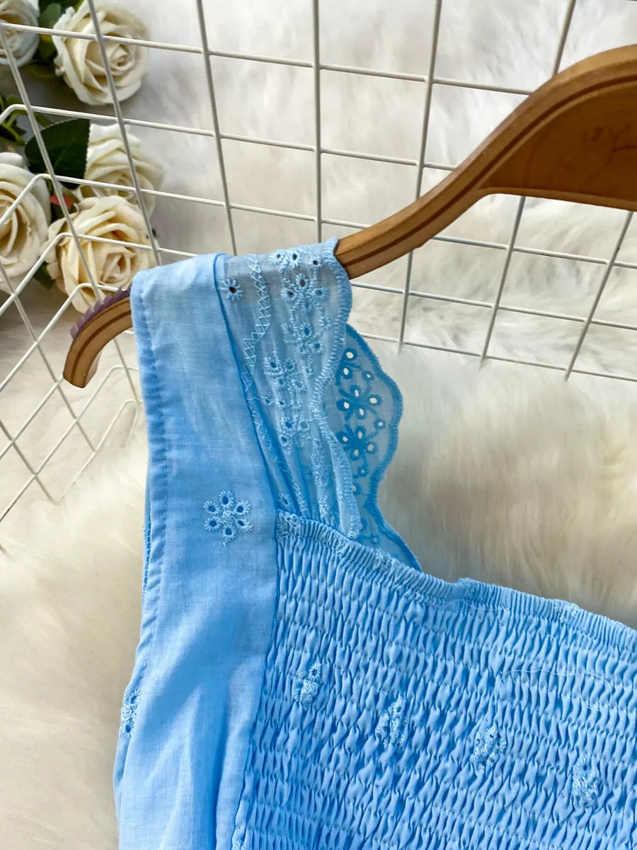 Blue eyelet maxi dress with smocked bodice and cutout detail on sleeve.